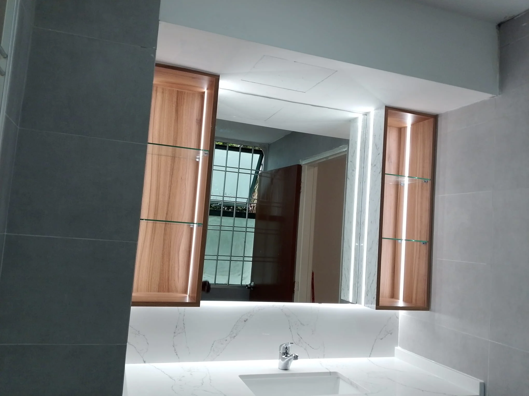 Renovated bathroom vanity with backlit mirror and timber cabinets